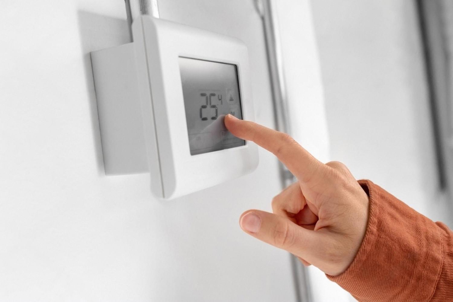 Person adjusting a smart thermostat set to 25 degrees inside a UAE home