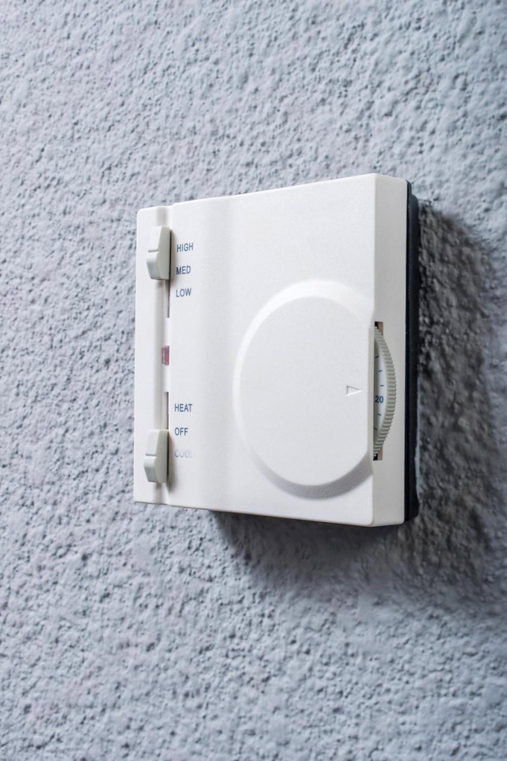 Wall-mounted analogue thermostat with heat and cool switch in a Dubai apartment
